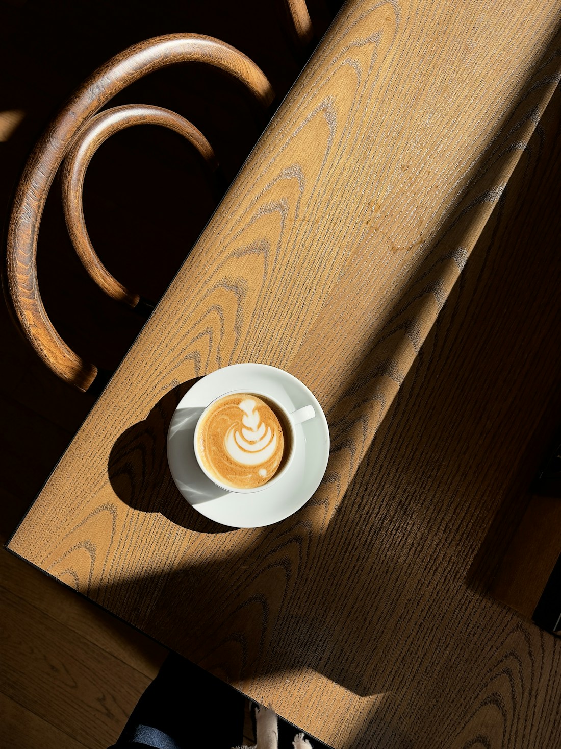 木のテーブルに置かれた、ラテアートを施した一杯のコーヒー